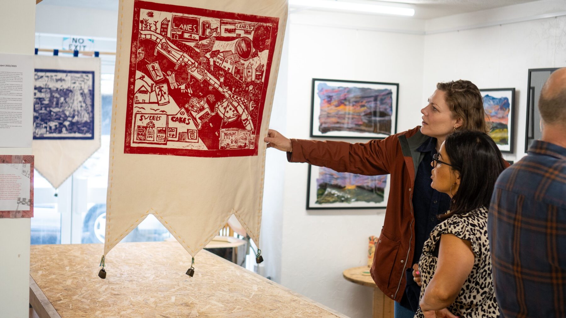 two women looking at a large colourful cloth art print